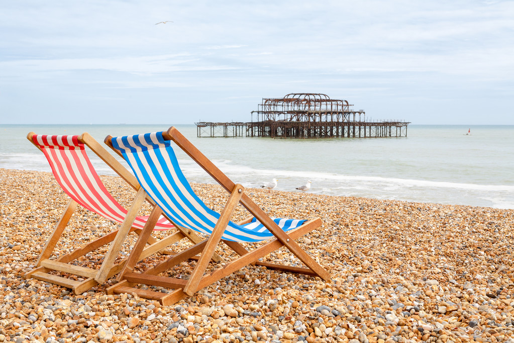 Two deckhairs on Brighton beach with West Pier behind. Brighton, East Sussex, England