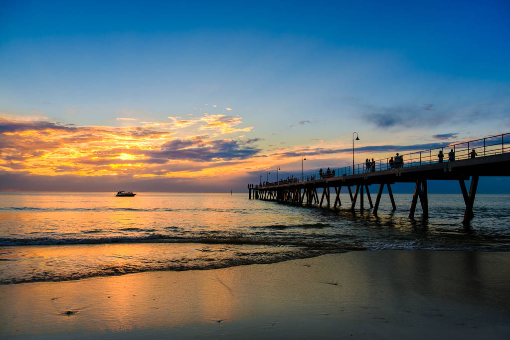 People walking along Glenelg Beach jetty at sunset, Adelaide, South Australia