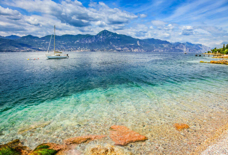 Idyllic lake Garda coastline in Malcesine with sailboats and mountains, Northern Italy