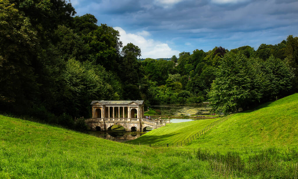 Mystical landscape, Prior Park, and Palladian Bridge. View for fresh grass, trees, river with blue sky.