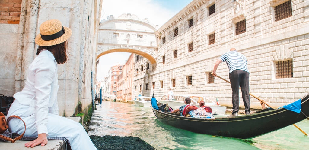 woman sitting at city quay at venice italy enjoying the view of canals with gondolas copy space